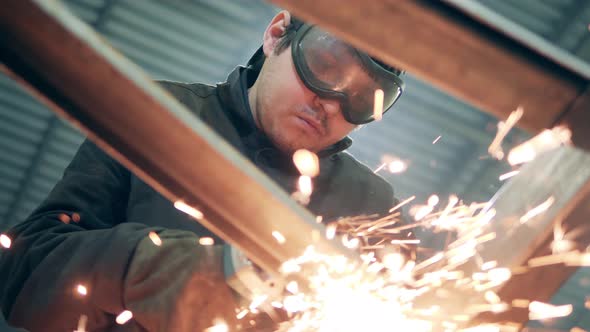 Welder in Protective Glasses Is Cutting Metal Producing Lots of Sparks