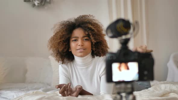 Nice Young Woman with Kinky Hair Lies on Bed and Tells Story