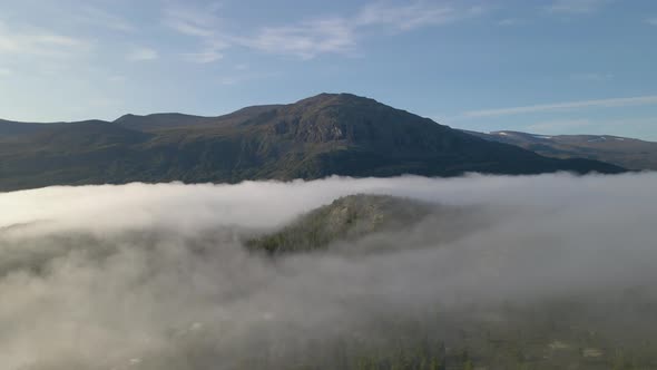 Aerial drone shot flying and panning over a mountain landscape with fog, Norway