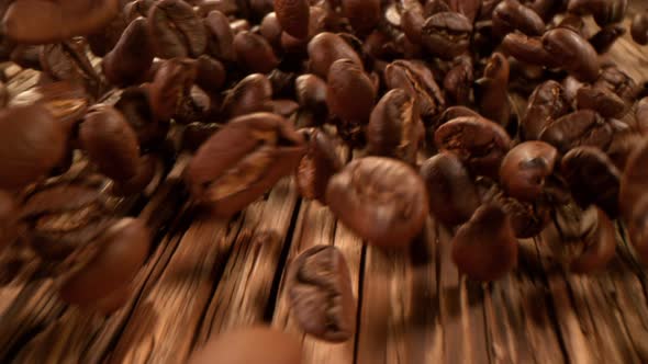Super Slow Motion Detail Shot of Coffee Beans Strewing Towards on Wooden Background at 1000Fps