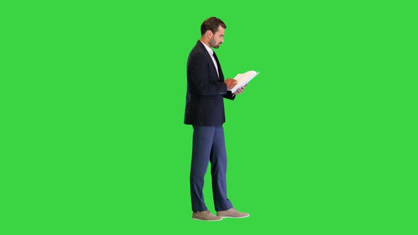 Young Business Man Looking Through the Documents on a Green Screen Chroma Key