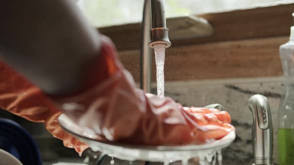 Hands in Orange Gloves Wash Dishes in the Kitchen