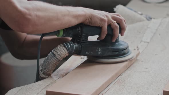 Carpentry Works Worker Makes the Top Surface of a Rectangular Wooden Detail Softer with a Grinding