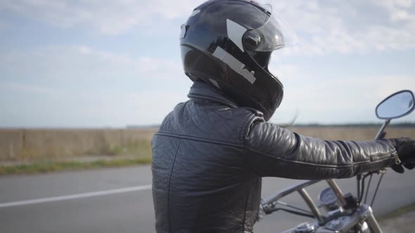 The Girl Wearing Black Helmet Sitting on the Motorcycle Looking Away on the Road