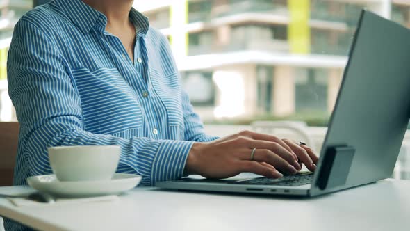 A Woman Is Typing on a Laptop While Being in a Cafe