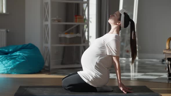 Wide Shot Pregnant Young Yogi Exercising Sitting Indoors at Home Breathing