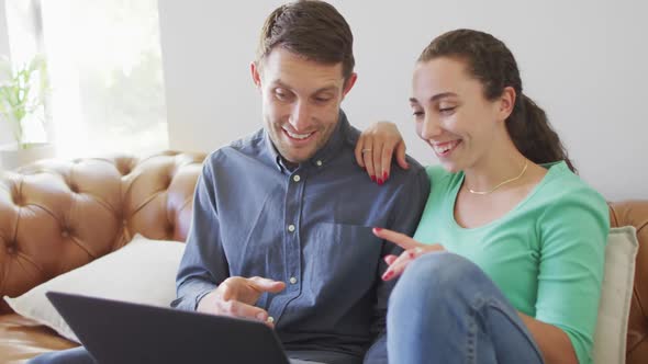 A young caucasian couple talking and paying their bills using a laptop