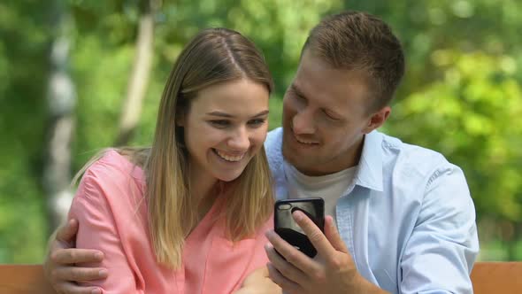 Cheerful Enamored Couple Watching Funny Video on Smartphone, Romantic Park Date