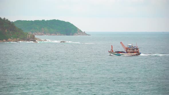 Local motor boat slowly floats on calm waves through the sea Bay