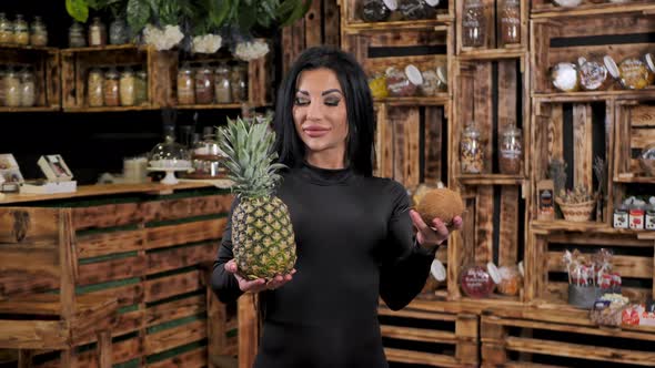 A Young Happy Woman is Holding and Selling Fresh Fruit in a Health Food Store