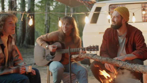 Happy Friends Singing to Guitar at Campsite