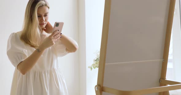 Attractive Blonde Making Selfie In Mirror Trying On New Dress In Modern Showroom