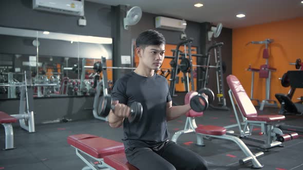 Fitness concept. Young asian men lifting dumbbells in the gym