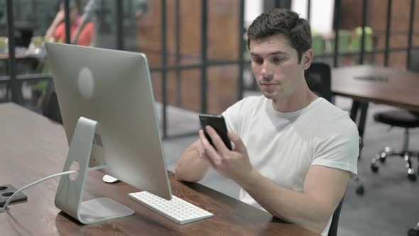 Young Man Using Smartphone at Work