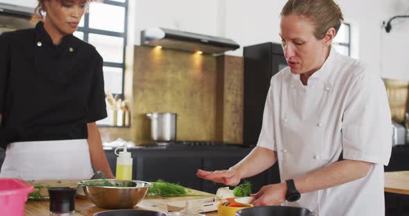 Caucasian female chef teaching diverse group wearing face masks