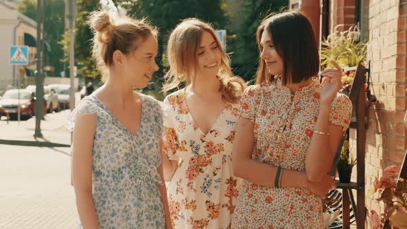 Three young beautiful girls posing outdoors at summer sunny day