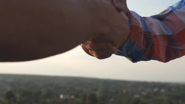 Friendly Handshake of Two Unrecognizable Men on Cityscape Background