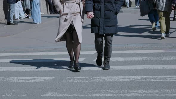 pair of a man and a woman crosses the road holding hands, lovers walk along the street of the city