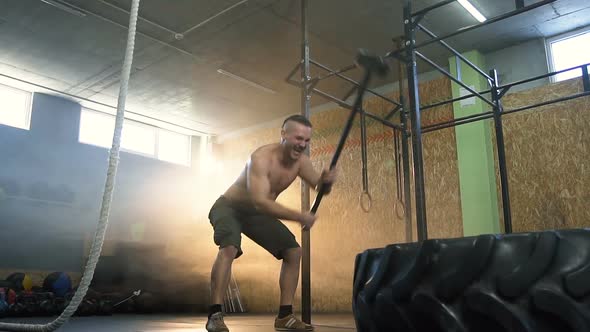 Strong Fit Man Beatting Tractor Ride Using Hammer During Crossfit Training