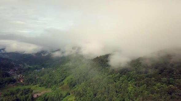 Aerial view flying thru the morning rain cloud covered tropical rain forest mountain landscape durin