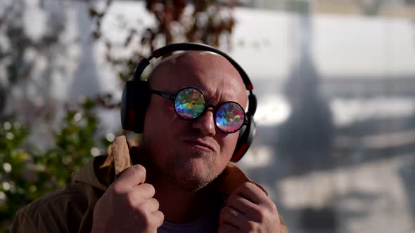 Cool Man with Wireless Headphones and Fashion Crystal Eyeglasses is Listening to Music