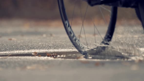 Cyclist Rides On Puddle. Cycling On Puddle On Bicycle. Triathlete On Triathlon. Water Spray Bicycle 