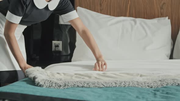 Female Housekeeper Making Bed in Hotel Room