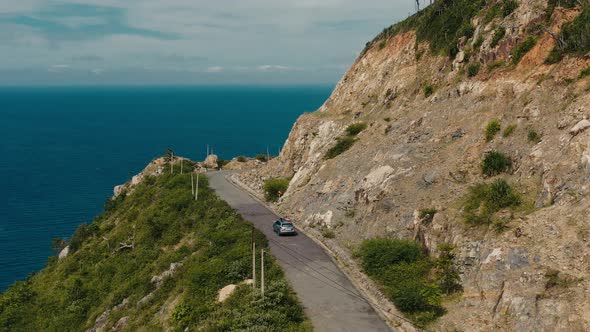 Aerial drone footage tracking an SUV car flying over an empty curve road