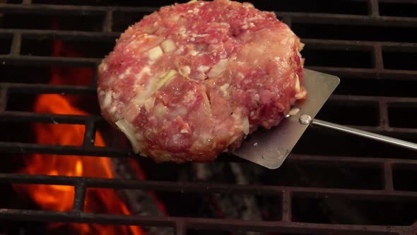 Raw Homemade Cutlet for a Burger Is Placed with a Kitchen Spatula on the Grill