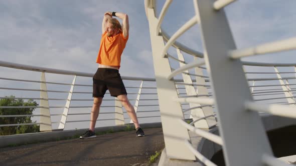 Sporty Caucasian man training on a bridge