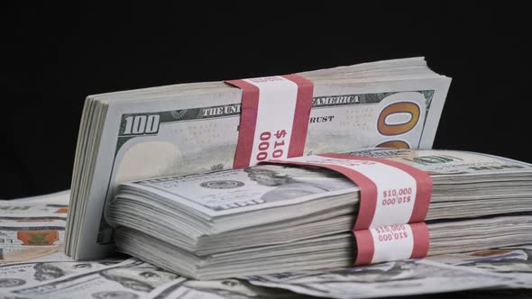 Bundles of Dollars Lying on a Pile of Money and Rotate on Black Background