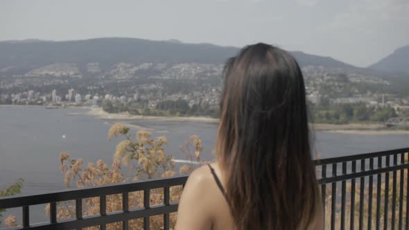 Young Asian girl enjoying view at Prospect point, Vancouver North Shore in background, Slowmo