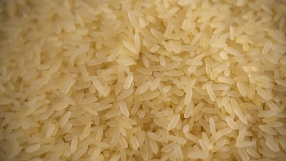 Rice is poured into a glass bowl on a black background. Slow motion.