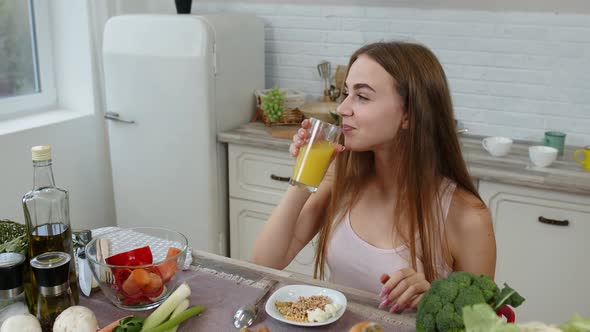 Girl Eating Raw Sprouts Buckwheat with Nuts, Drinking Orange Juice in Kitchen. Weight Loss and Diet
