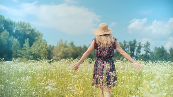 Girl Enjoying In Green Grass Field. Woman Walking In Summer Field. Romantic Girl In Wicker Hat.