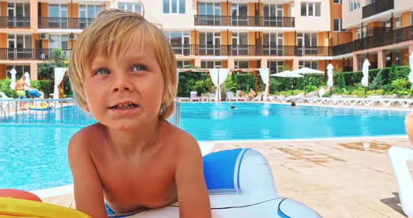 Happy Little Boy Sitting near the Pool