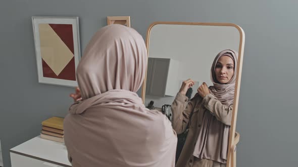Woman Putting on Hijab in front of Mirror at Home