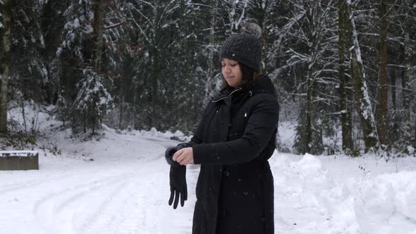 Young Thai woman puts on black leather gloves and stretches in winter scenery.