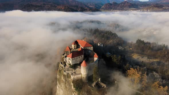 Impressive Bled castle surrounded by low-hanging mist, golden hour, Slovenia