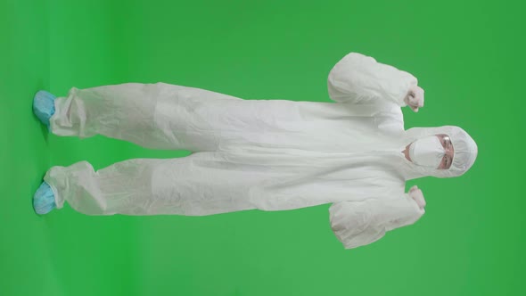 Asian Man Wear Protective Uniform PPE, Medical Face Mask And Celebrating In The Green Screen Studio