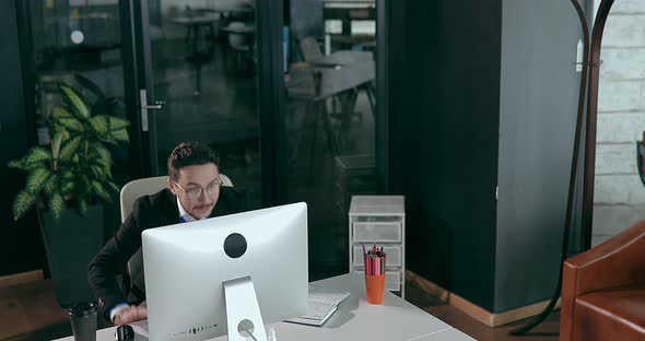 Businessman in Office in Front of Computer Showing Happy Emotions