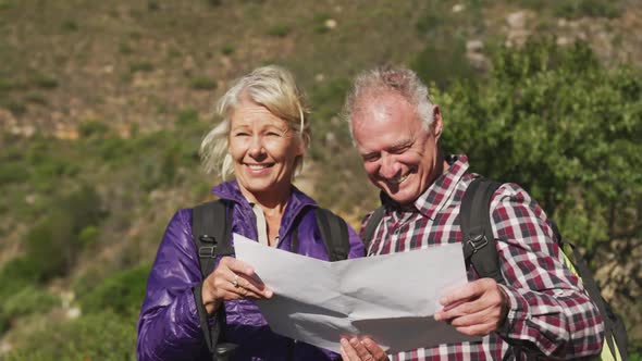 Happy senior couple looking at map in moutains