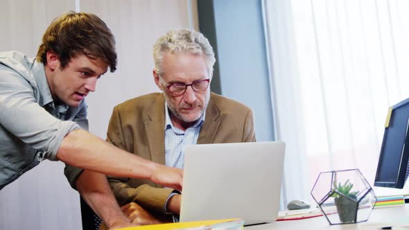 Businessman and coworker discussing over laptop