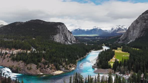 Drone camera takes off over a rough river flows between the wooded slopes of the mountains