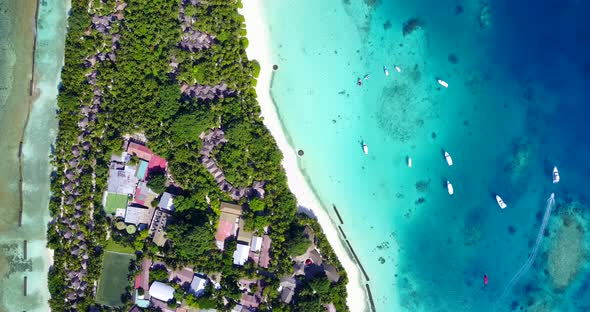 Wide angle overhead tourism shot of a sandy white paradise beach and aqua blue water background in c