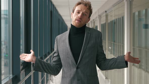 Young handsome man in fashion shirt spreading his arms, raising shoulders.