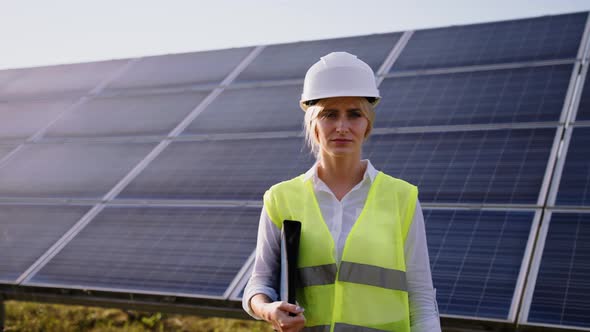 Portrait of Beautiful Female Engineer Technologist Standing Among Solar Panels