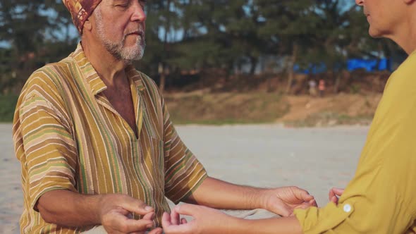 Crop of Senior Couple Sits and Meditating Together on Sandy Beach