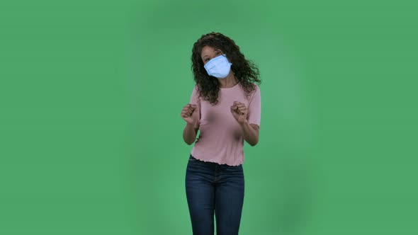 Portrait of Beautiful African American Young Woman in Medical Mask Is Looking Straight Dancing Funny