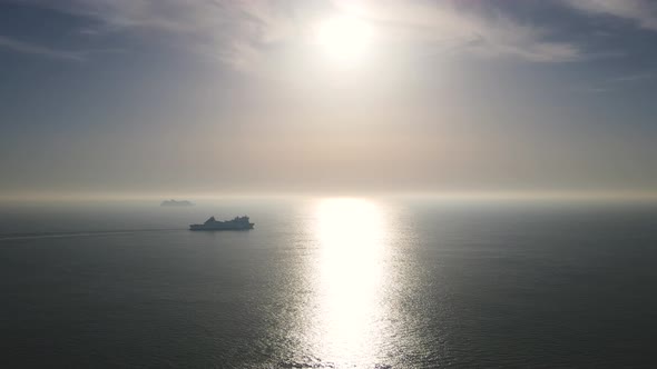 Silhouette of cruise ship navigating on silver sea water. Aerial forward